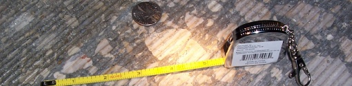 Coin and tape measure on textured pavement