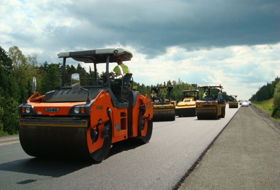 Multiple intelligent compaction rollers compact asphalt during pavement construction.